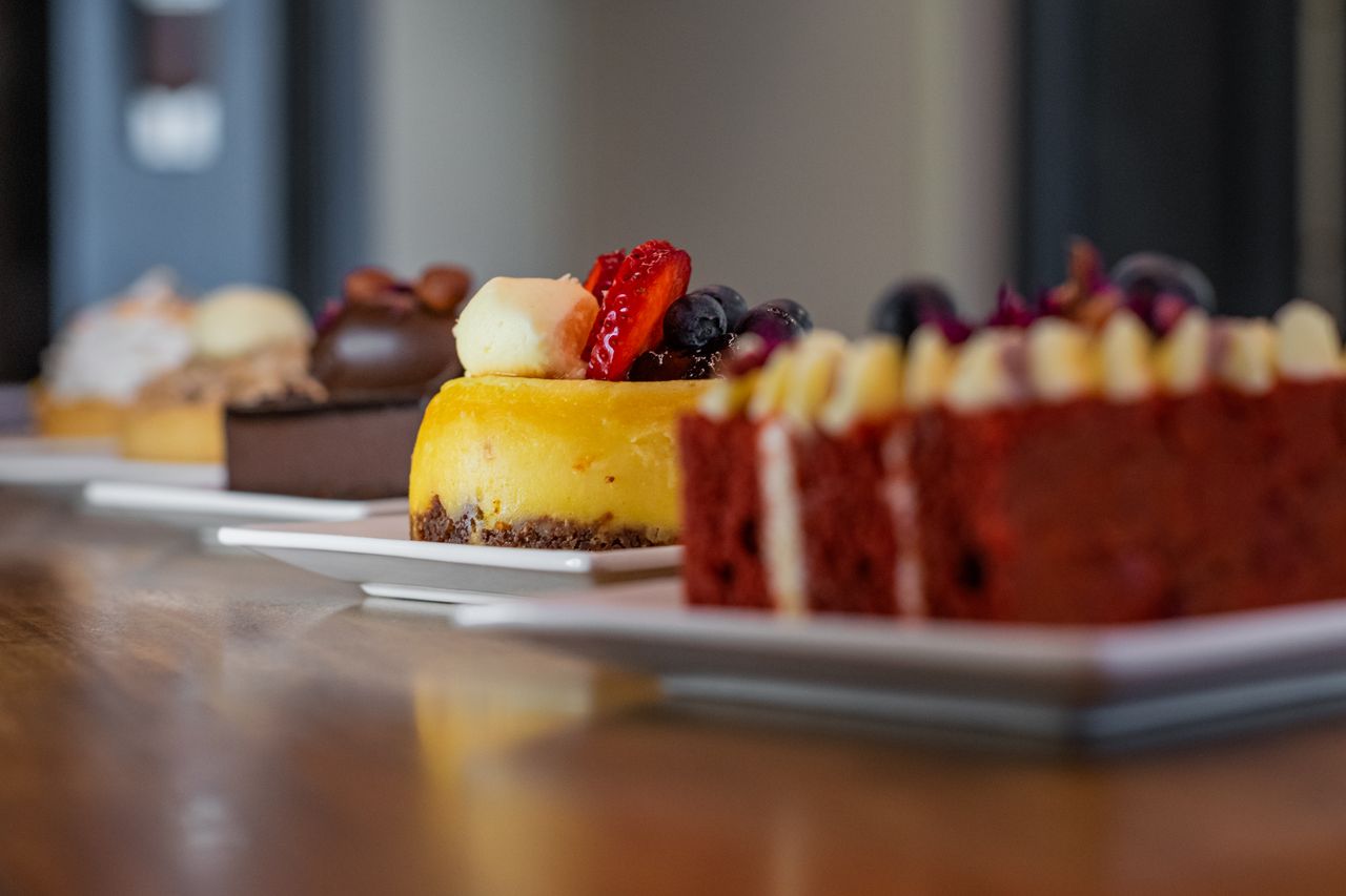 Close-up of assorted gourmet desserts on plates, featuring cheesecake, chocolate cake, and red velvet.